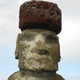 A red scoria pukao restored atop a moai.